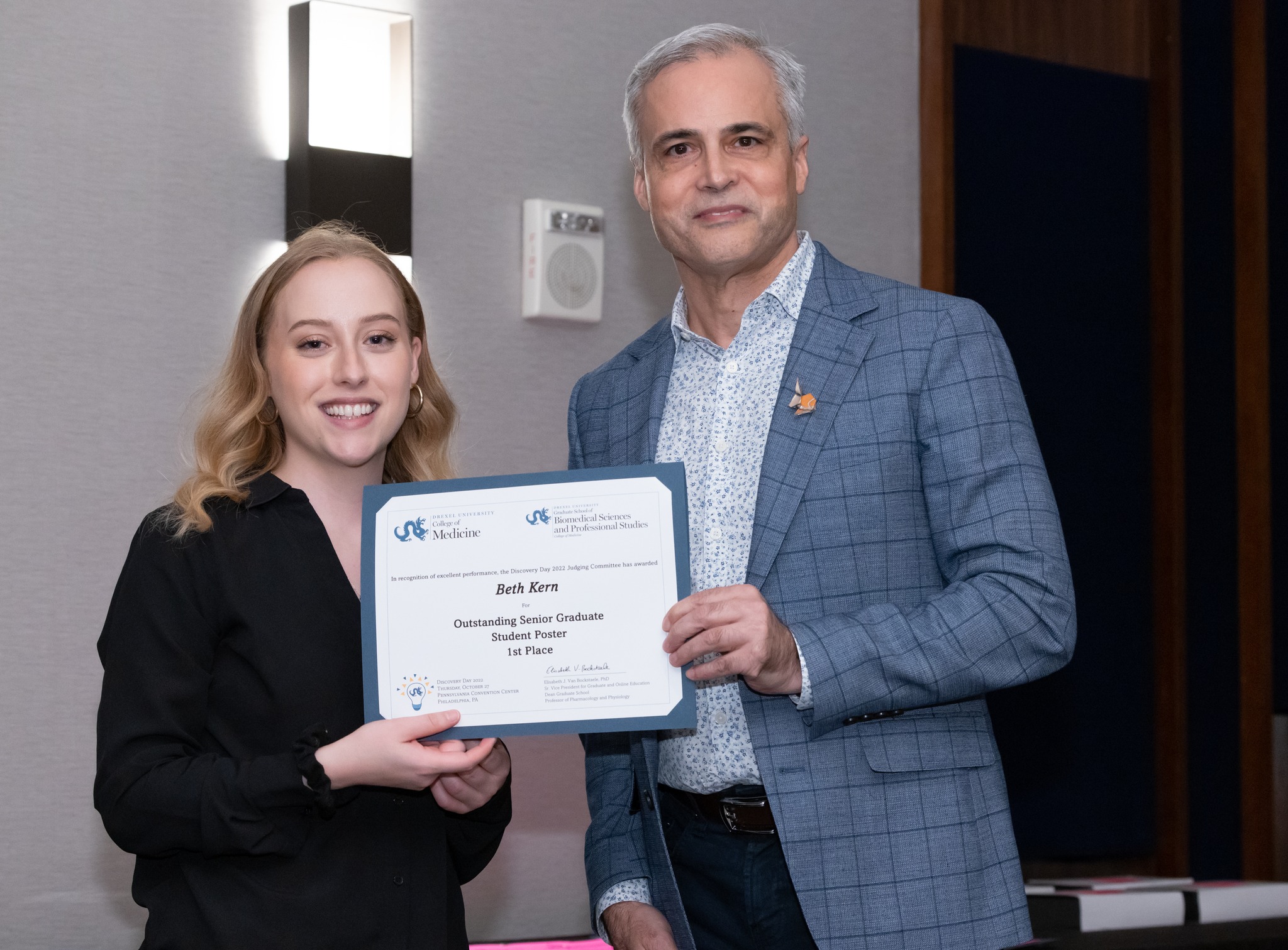 Female student on left holding certificate with male faculty member on right